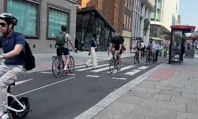 Moment pedestrians narrowly avoid being run down by cyclists who fail to stop for bike lane zebra crossing at one of Sadiq Khan's 'floating bus stops'